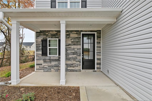 property entrance featuring stone siding and covered porch