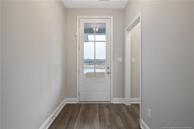 doorway with dark wood-type flooring, visible vents, and baseboards