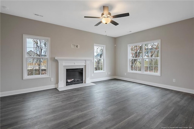 unfurnished living room with baseboards, visible vents, dark wood finished floors, ceiling fan, and a premium fireplace