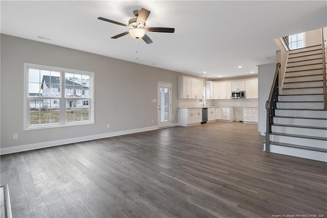 unfurnished living room featuring dark wood-style flooring, recessed lighting, a ceiling fan, baseboards, and stairs