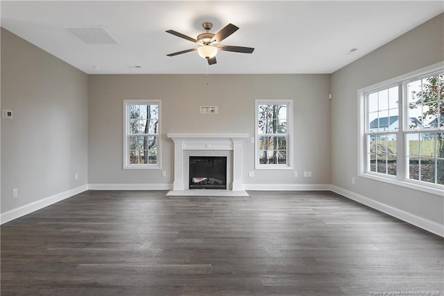 unfurnished living room featuring a fireplace with flush hearth, dark wood finished floors, visible vents, and plenty of natural light