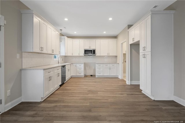 kitchen with light stone counters, stainless steel appliances, dark wood-style flooring, a sink, and white cabinetry