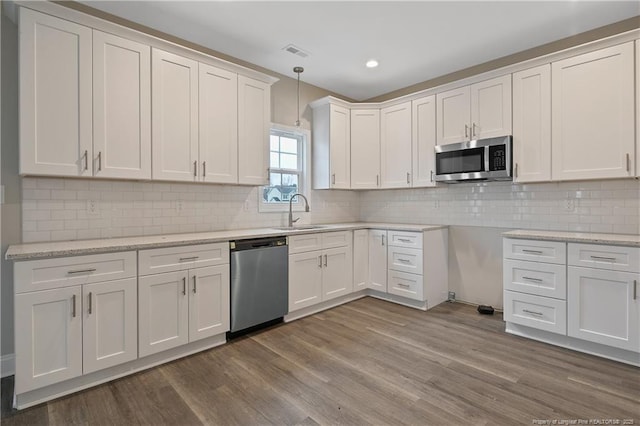 kitchen with white cabinets, visible vents, stainless steel appliances, and decorative light fixtures