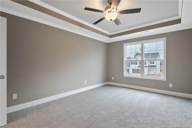 unfurnished room featuring baseboards, a raised ceiling, light colored carpet, and crown molding