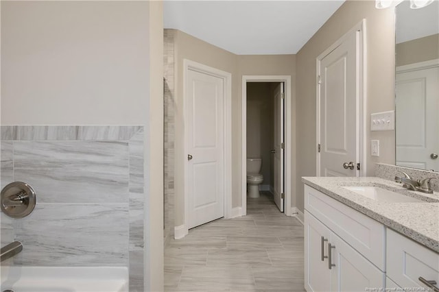 full bathroom featuring a shower, vanity, toilet, and baseboards