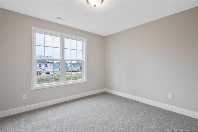 empty room featuring carpet flooring, visible vents, and baseboards