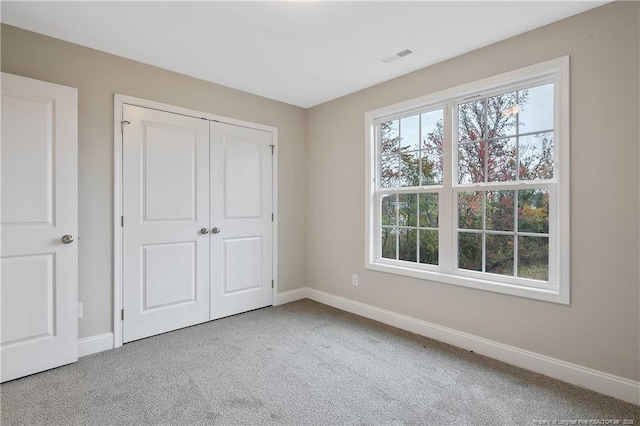 unfurnished bedroom with a closet, carpet flooring, visible vents, and baseboards