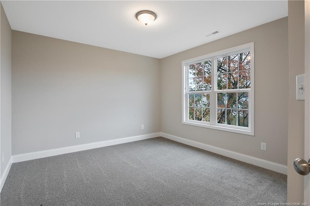 carpeted spare room featuring visible vents and baseboards