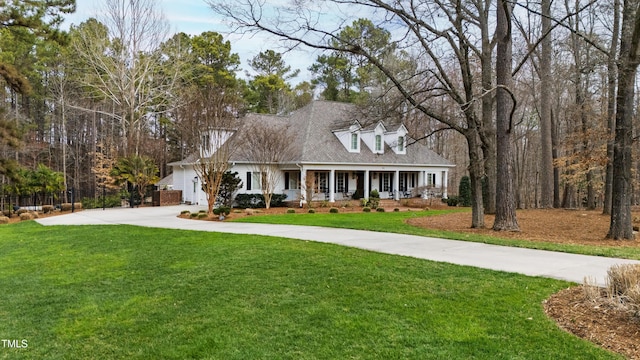 cape cod house featuring covered porch, concrete driveway, a front lawn, and fence