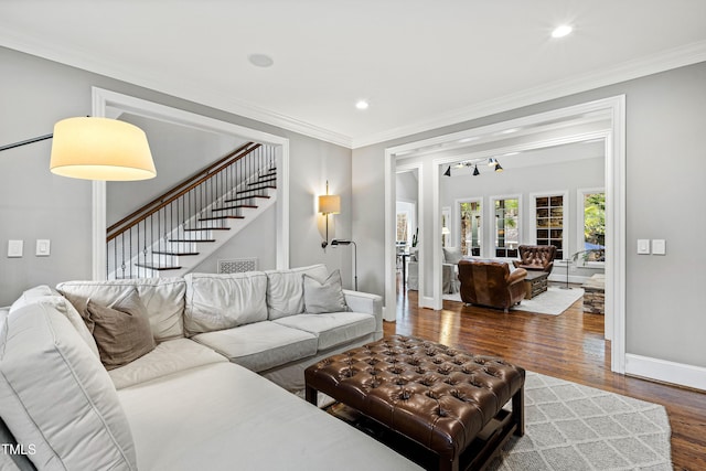 living room with stairs, crown molding, baseboards, and wood finished floors