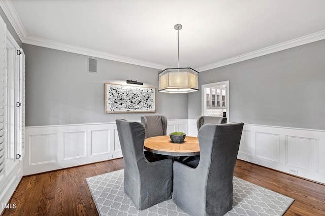 dining space featuring a wainscoted wall, visible vents, dark wood finished floors, and crown molding