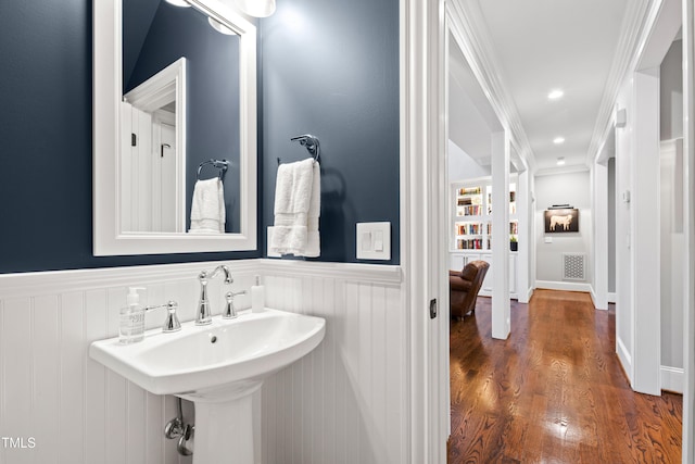 bathroom featuring visible vents, wood finished floors, ornamental molding, and wainscoting