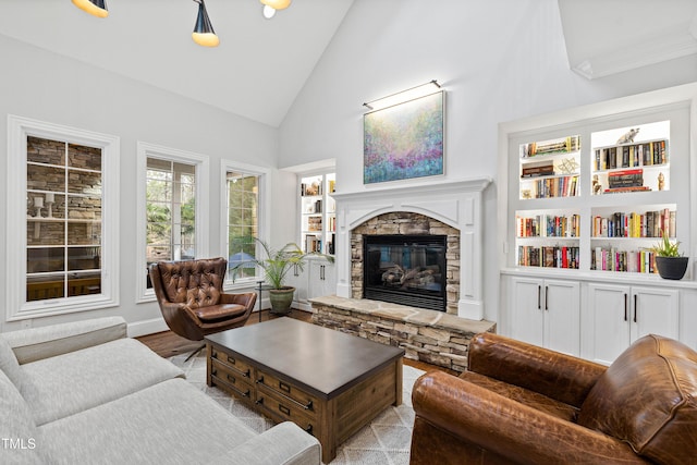 living area featuring light wood-type flooring, high vaulted ceiling, and a stone fireplace