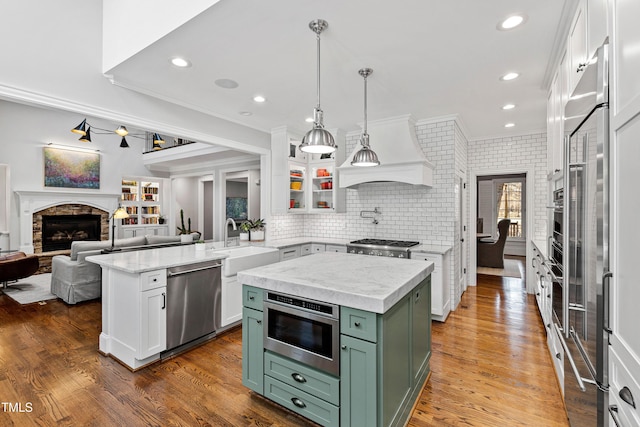 kitchen with premium range hood, open floor plan, white cabinetry, stainless steel appliances, and green cabinetry