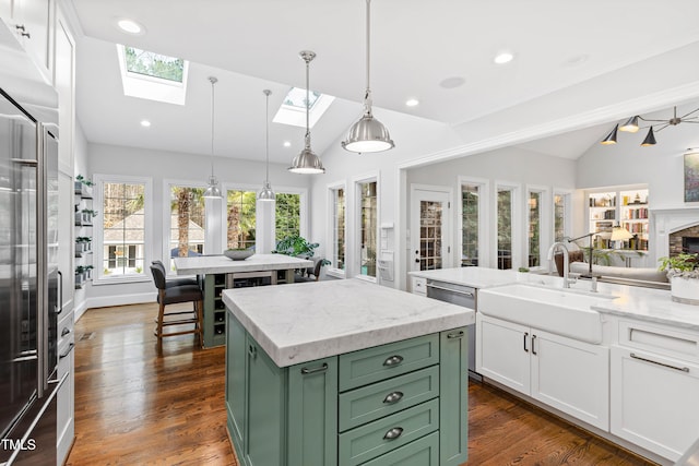 kitchen featuring green cabinets, lofted ceiling with skylight, white cabinets, and a sink