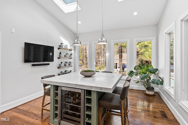 dining room featuring dark wood-style floors, beverage cooler, a skylight, and baseboards