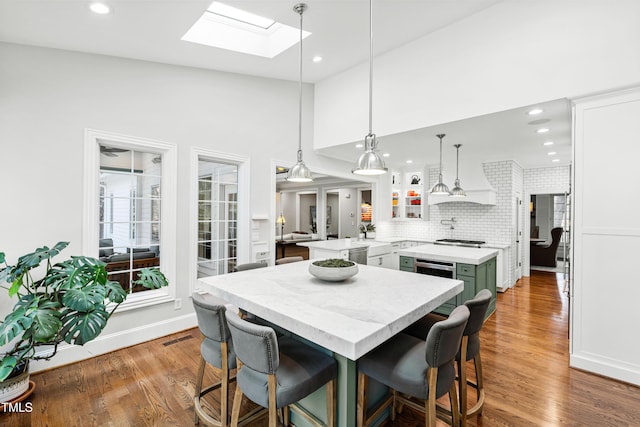 kitchen featuring visible vents, a kitchen island, wood finished floors, and white cabinetry