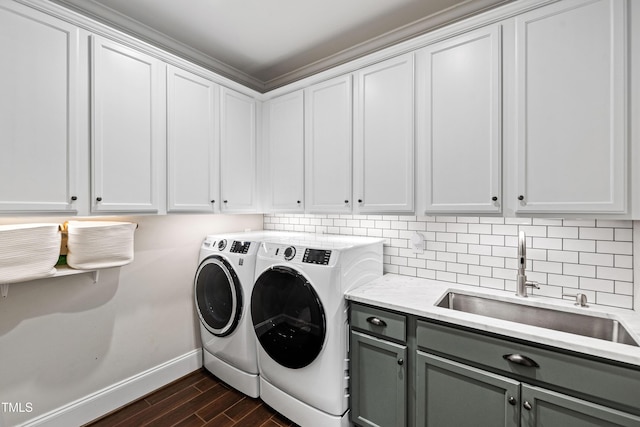 clothes washing area featuring washing machine and clothes dryer, baseboards, wood tiled floor, cabinet space, and a sink