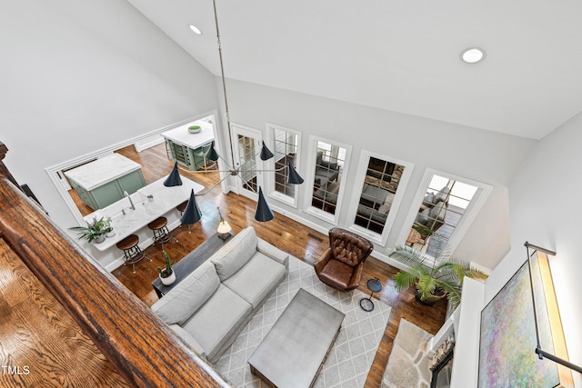 living room with recessed lighting, baseboards, high vaulted ceiling, and wood finished floors