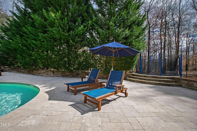 view of swimming pool with a patio, a trampoline, fence, and a fenced in pool