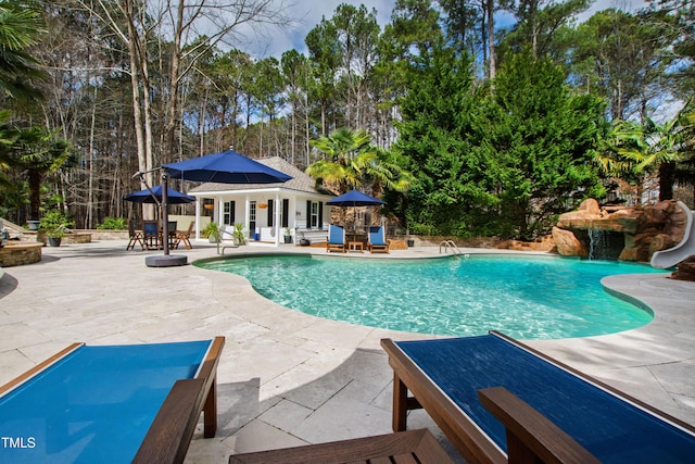 pool with a patio, a water slide, an outdoor structure, and an exterior structure