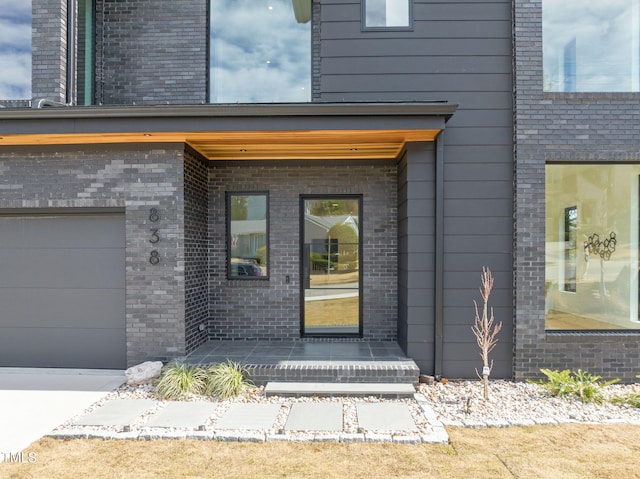 entrance to property with a garage and brick siding