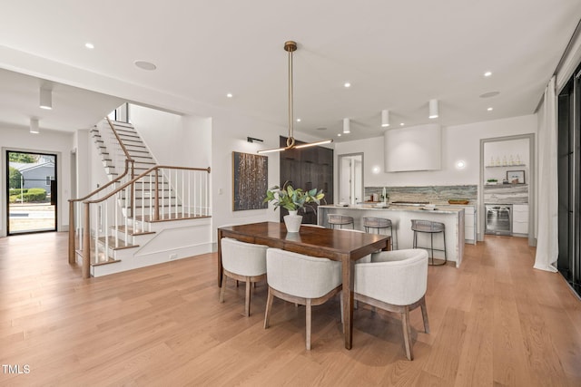 dining area featuring light wood-style floors, beverage cooler, stairway, and recessed lighting