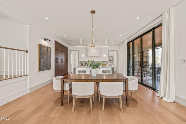 dining space featuring baseboards, a wall of windows, recessed lighting, and light wood-style floors