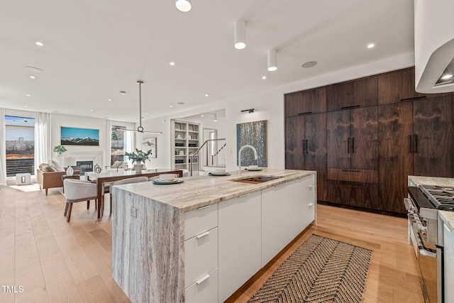 kitchen featuring range with two ovens, a fireplace, white cabinets, a sink, and modern cabinets