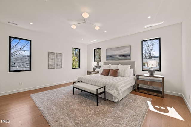 bedroom with wood-type flooring, visible vents, baseboards, and recessed lighting