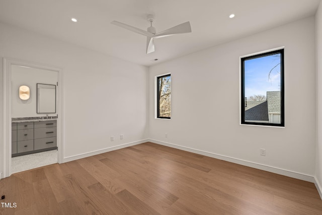 unfurnished bedroom featuring recessed lighting, a sink, baseboards, and wood finished floors