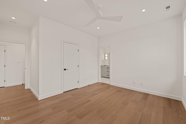 unfurnished bedroom featuring light wood-style flooring, visible vents, baseboards, and ensuite bathroom