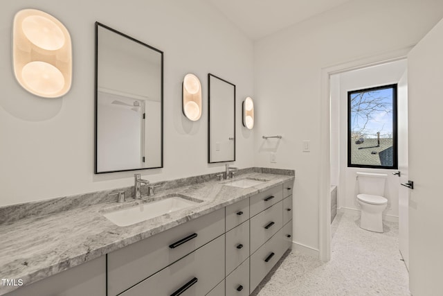 full bath featuring baseboards, a sink, toilet, and double vanity