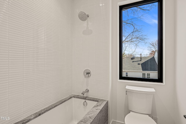 full bathroom with tiled shower / bath combo and toilet