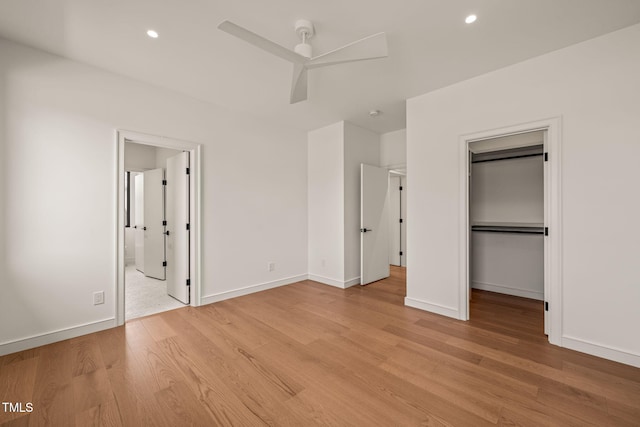 unfurnished bedroom with baseboards, ensuite bath, a spacious closet, light wood-style floors, and recessed lighting