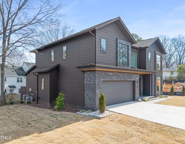 view of front of home featuring driveway, a garage, a front lawn, central AC, and brick siding