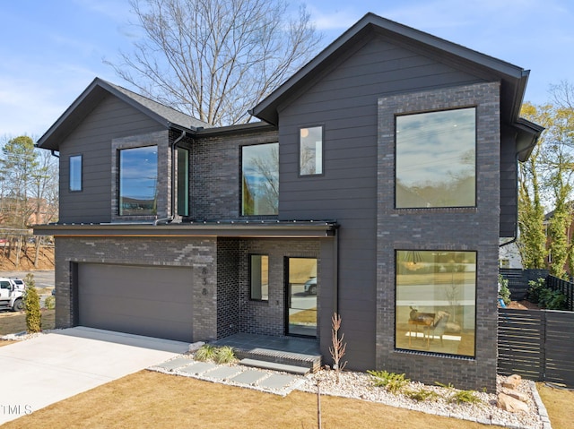 contemporary house featuring a garage, brick siding, fence, and driveway