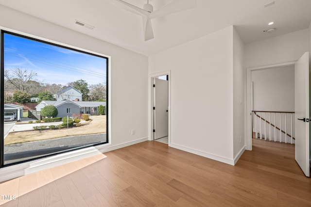 empty room with baseboards, visible vents, ceiling fan, and wood finished floors