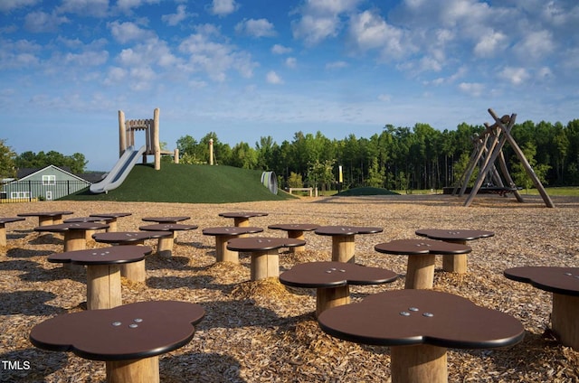 view of yard with playground community, fence, and a view of trees