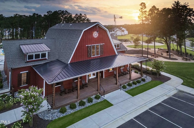 exterior space with metal roof, covered porch, a barn, a gambrel roof, and a yard