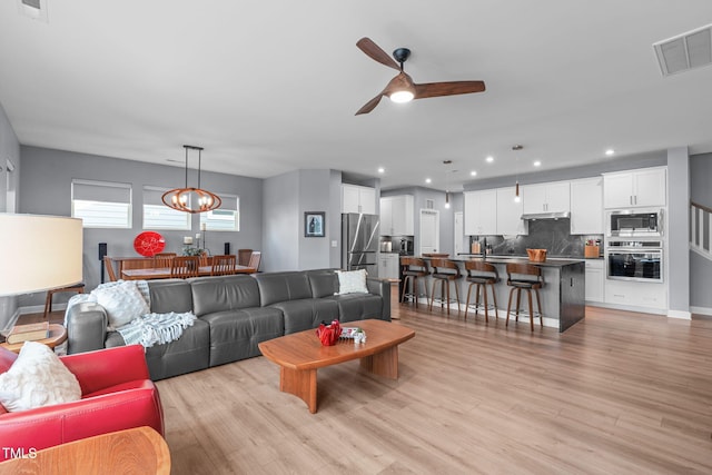 living area featuring recessed lighting, a ceiling fan, baseboards, visible vents, and light wood finished floors