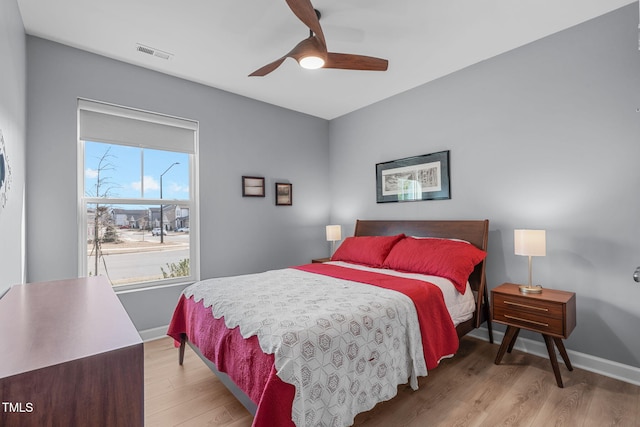 bedroom with baseboards, a ceiling fan, visible vents, and light wood-style floors