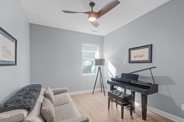 living area featuring light wood-style floors, baseboards, visible vents, and a ceiling fan