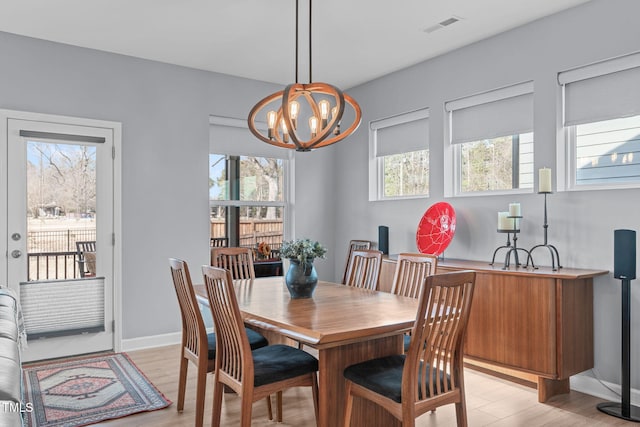 dining space featuring a chandelier, visible vents, light wood-style flooring, and baseboards