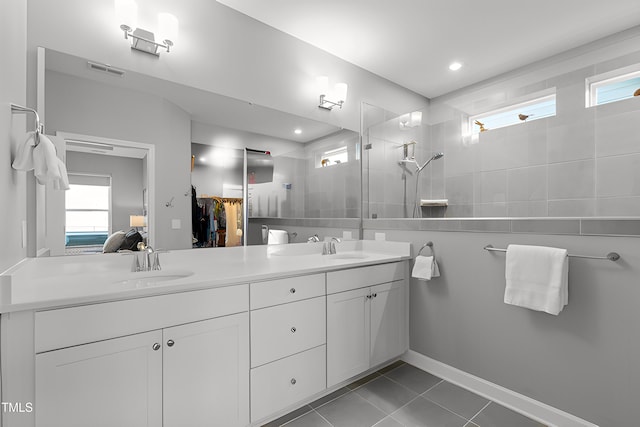 ensuite bathroom featuring double vanity, visible vents, ensuite bath, walk in shower, and a sink