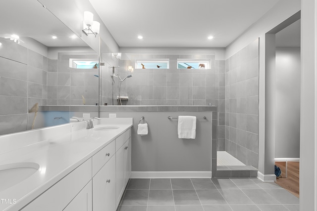 full bath with double vanity, a walk in shower, a sink, and tile patterned floors