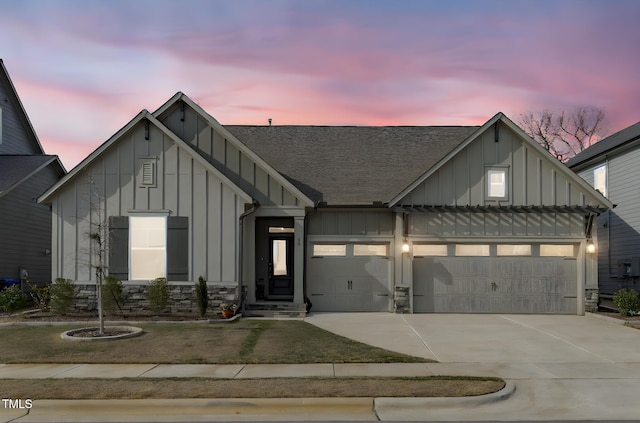 modern farmhouse style home featuring driveway, stone siding, board and batten siding, and an attached garage