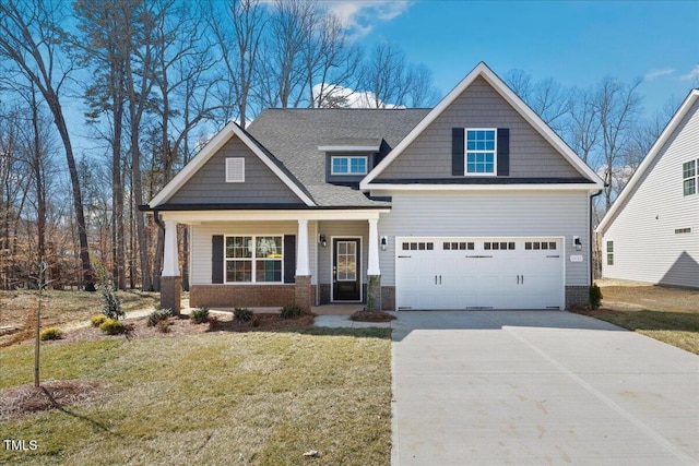 craftsman house with a garage, driveway, brick siding, and a front yard