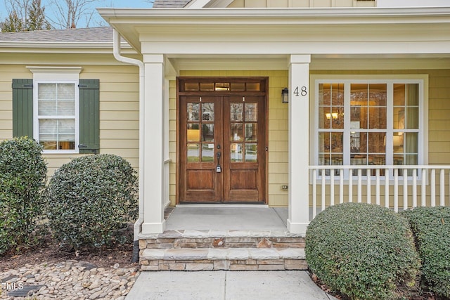 doorway to property featuring french doors, board and batten siding, and a shingled roof