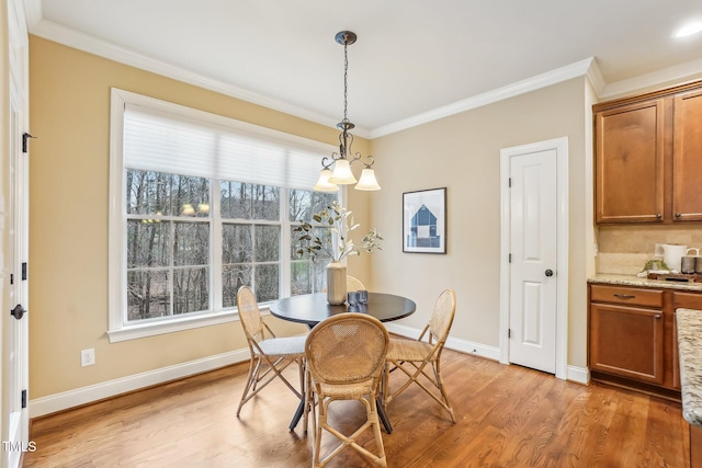 dining area featuring crown molding, light wood-style flooring, and baseboards